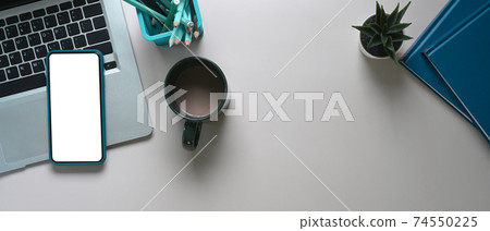Top view of smart phone with blank screen, laptop, coffee cup and notebook on white table. Top view of smart phone with blank screen, laptop, coffee cup and notebook on white table. 74550225