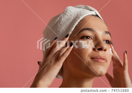 Joyful female using recommended skin treatment i 74551880