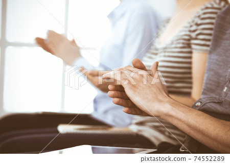 Business people clapping at meeting or conference, close-up of hands. Group of unknown businessmen and women in modern white office. Success teamwork, corporate coaching and applause concept 74552289