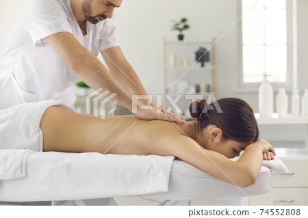 Woman patient getting massage of back from professional chiropractor or masseur in clinic Woman patient getting massage of back from professional chiropractor or masseur in clinic 74552808