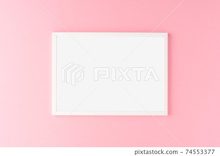 Empty photo frame hanging on pink wall. Mockup 74553377