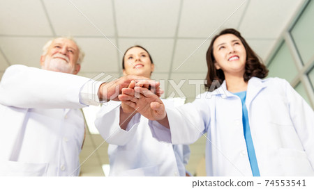 Close up hands team of medical workers holding hands together in hospit Close up hands team of medical workers holding hands together in hospit 74553541