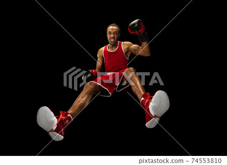 Young african-american boxer in action, motion isolated on black background, look from the bottom. Concept of sport, movement, energy and dynamic. 74553810