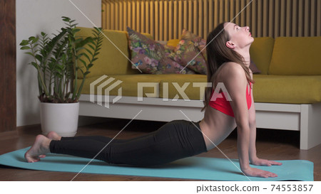 Young woman practices yoga on a mat at home in the evening 74553857