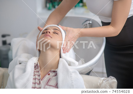 Hairdresser drying her clients hair with a towel Hairdresser drying her clients hair with a towel 74554028