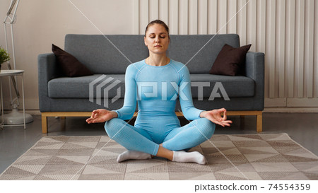 Time for yoga. Attractive young woman exercising and sitting in yoga position 74554359