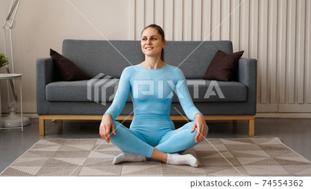 Time for yoga. Attractive young woman exercising and sitting in yoga position 74554362