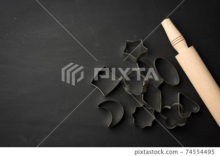 metal cookie cutters and wooden rolling pin on a black background metal cookie cutters and wooden rolling pin on a black background 74554495