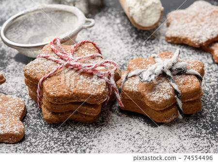 Star shaped baked gingerbread cookies sprinkled with powdered sugar on a black table 74554496