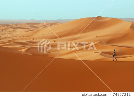Man walking in desert on duna edge Man walking in desert on duna edge 74557211