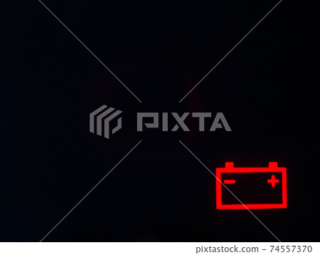 Red battery icon on a black background. Car battery discharge concept, copy space for text 74557370