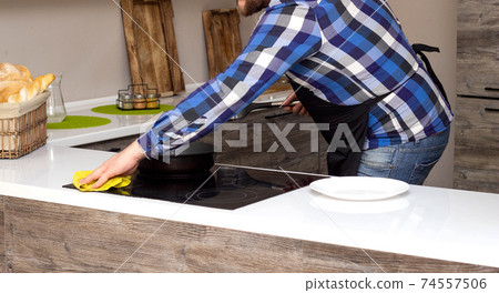 A man with a beard does the cleaning in the modern kitchen, home cleaning, domestic A man with a beard does the cleaning in the modern kitchen, home cleaning, domestic 74557506