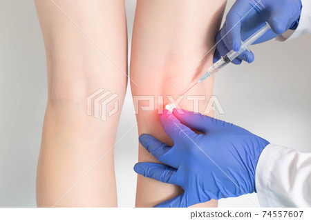 The doctor makes an injection into the periarticular tissue, in which there is pain behind the knee and intravascular pathologies, close-up The doctor makes an injection into the periarticular tissue, in which there is pain behind the knee and intravascular pathologies, close-up 74557607