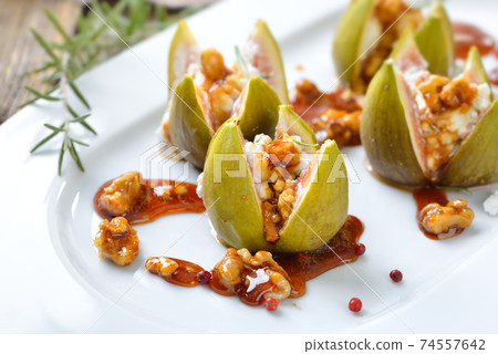 Baked figs stuffed with goats cream cheese and candied walnuts with sweet honey and rosemary Baked figs stuffed with goats cream cheese and candied walnuts with sweet honey and rosemary 74557642