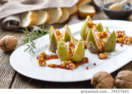 Baked figs stuffed with goats cream cheese and candied walnuts with sweet honey and rosemary Baked figs stuffed with goats cream cheese and candied walnuts with sweet honey and rosemary 74557643