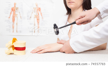 A neurologist doctor checks the brachio radial reflex on the arm of a girl patient. Neurological disorders and diseases, background A neurologist doctor checks the brachio radial reflex on the arm of a girl patient. Neurological disorders and diseases, background 74557783