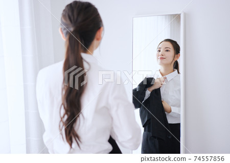 一個年輕的商業女人在鏡子前換衣服 74557856