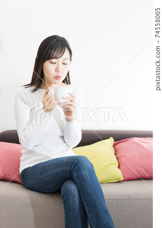 Woman drinking hot coffee on the couch 74558005