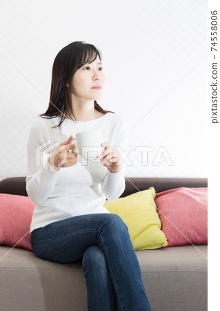 Woman drinking hot coffee on the couch Woman drinking hot coffee on the couch 74558006