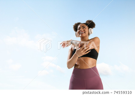 Portrait of female fashion model on blue sky background. Style and beauty concept, bright appearance. Lifestyle sport. 74559310