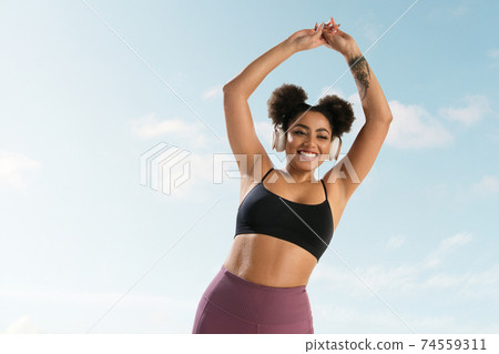 Portrait of female fashion model on blue sky background. Style and beauty concept, bright appearance. Lifestyle sport. 74559311