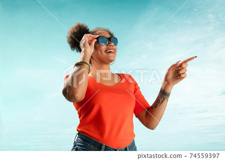 Portrait of female fashion model on blue sky background. Style and beauty concept, bright appearance 74559397
