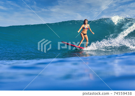 Female surfer on a blue wave Female surfer on a blue wave 74559438