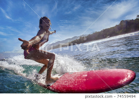 Female surfer on a blue wave 74559494