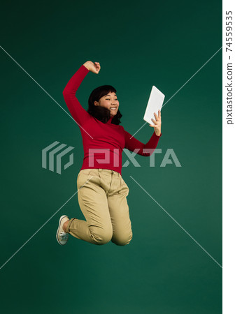 East asian woman's portrait isolated on green studio background with copyspace 74559535