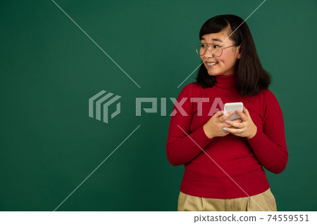 East asian woman's portrait isolated on green studio background with copyspace 74559551