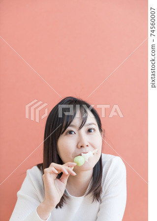 A woman lying down in a Japanese-style room and eating dumplings A woman lying down in a Japanese-style room and eating dumplings 74560007