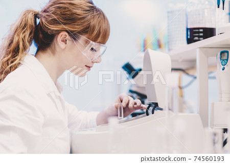 Attractive young scientist pipetting. Attractive young scientist pipetting. 74560193