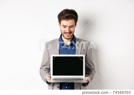 Handsome caucasian businessman in suit showing empty laptop screen, demonstrate promo, standing on white background Handsome caucasian businessman in suit showing empty laptop screen, demonstrate promo, standing on white background 74560703