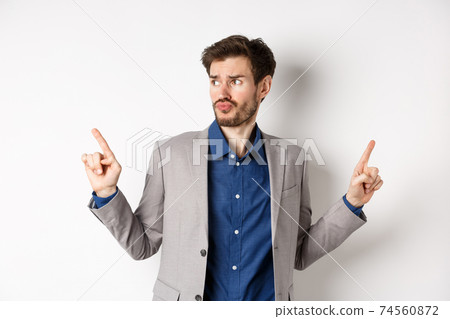 Complicated businessman pointing two ways, troubled to choose, looking aside and thinking, making decision, standing on white background in suit Complicated businessman pointing two ways, troubled to choose, looking aside and thinking, making decision, standing on white background in suit 74560872