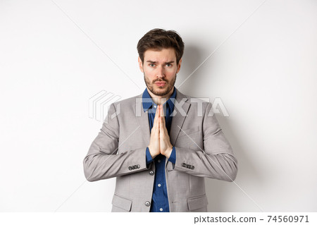Sad cute business man need help, say please or sorry, showing begging gesture, asking for favour, standing on white background 74560971