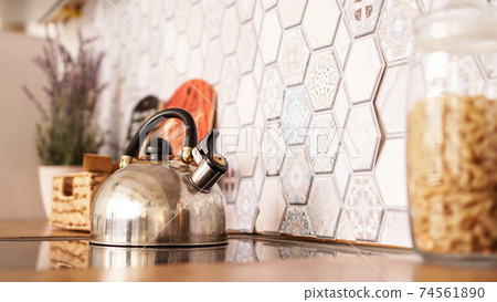 Metal kettle on the stove. Modern cozy kitchen Metal kettle on the stove. Modern cozy kitchen 74561890