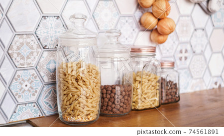 Pasta in glass jars. Pasta on a wooden countertop in a modern bright kitchen 74561891