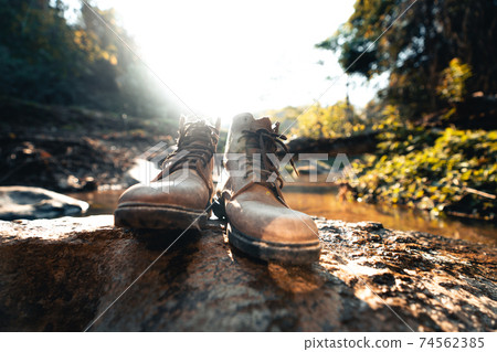 Leather boots on a rock in a natural stream. 74562385