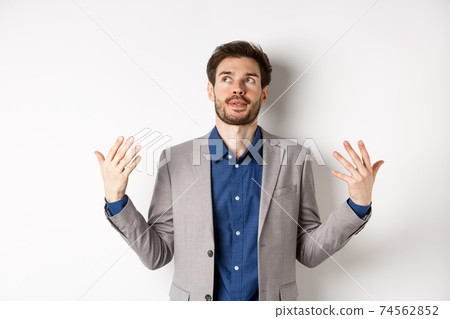 Tensed young manager in suit need some air, waving at himself as feeling flushed and annoyed, standing on white background Tensed young manager in suit need some air, waving at himself as feeling flushed and annoyed, standing on white background 74562852