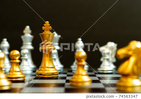 Gold king in chess game face with the another silver team on black background (Concept for company strategy, business victory or decision) 74563347