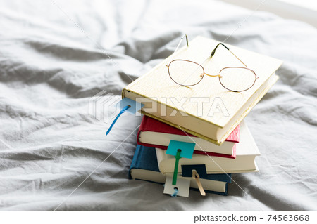 Books stacked on the bed Books stacked on the bed 74563668