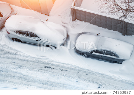 Top aerial view of apartment office building parking lot with many cars covered by snow stucked after heavy blizzard snowfall winter day. Snowdrifts and freezed vehicles. Extreme weather conditions Top aerial view of apartment office building parking lot with many cars covered by snow stucked after heavy blizzard snowfall winter day. Snowdrifts and freezed vehicles. Extreme weather conditions 74563987