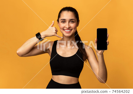 Happy sporty woman showing cellphone with blank screen Happy sporty woman showing cellphone with blank screen 74564202