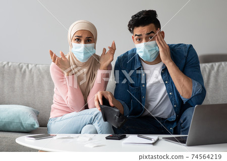 Worried couple in face masks with empty wallet 74564219