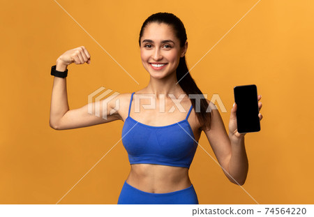 Happy sporty woman showing phone with blank screen Happy sporty woman showing phone with blank screen 74564220