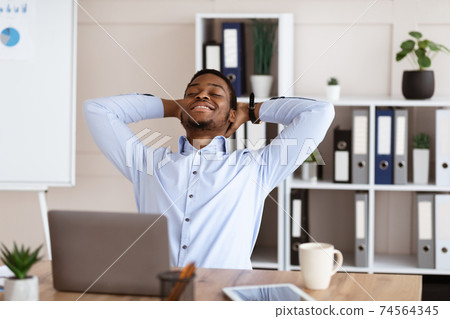 Joyful african american employee resting on his chair 74564345
