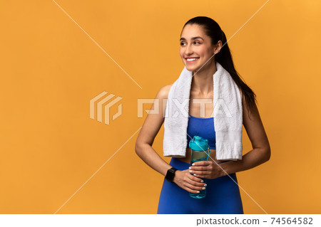 Sporty smiling woman standing with water bottle 74564582