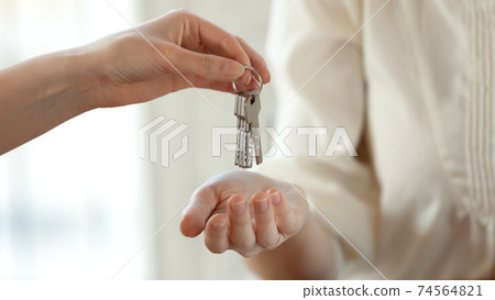 Close up young female realtor giving keys to happy buyer. 74564821