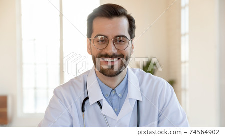 Smiling pleasant young doctor consulting patient online. 74564902