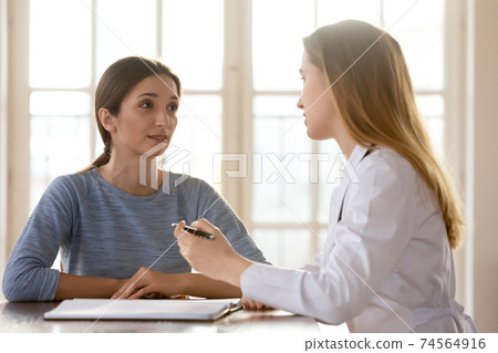 Happy young woman listening to female general practitioner. 74564916